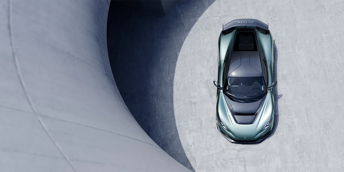 Close-up of the Rimac Nevera R seat and interior showing premium leather, contrast stitching, and carbon-fiber trim with the Nevera R logo.