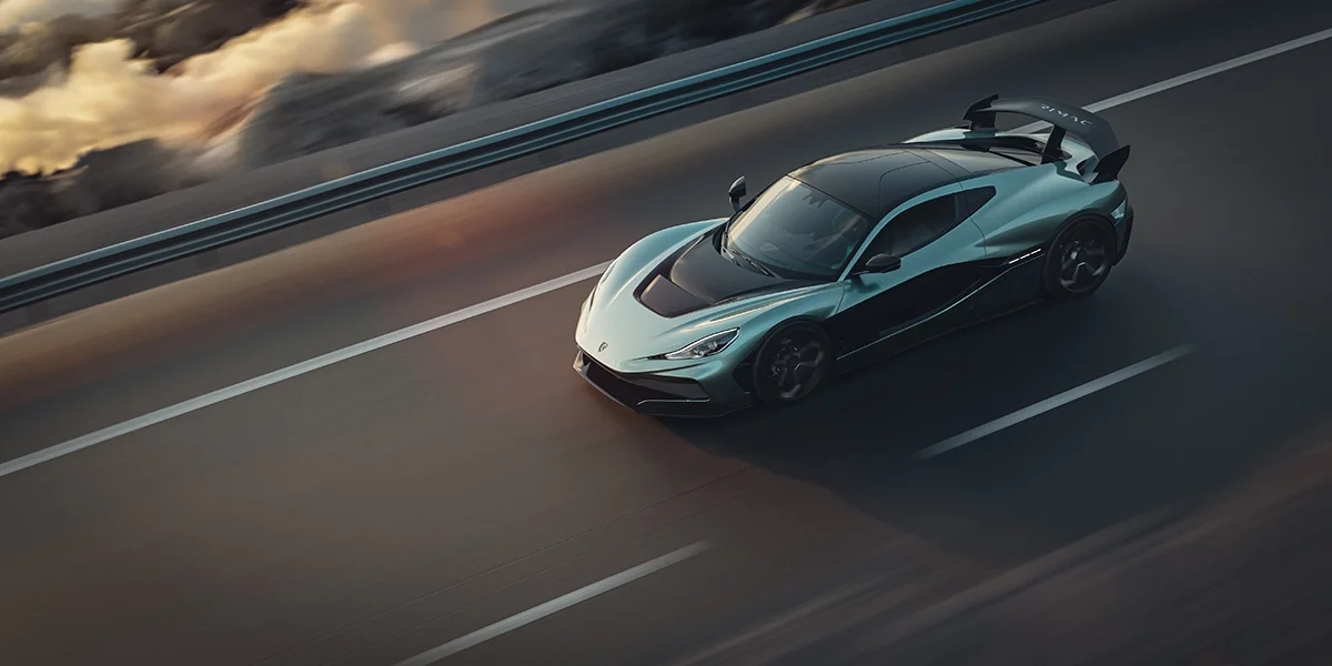 Side profile of the Rimac Nevera R driving through mountain roads at golden hour, demonstrating its streamlined silhouette and carbon-fiber elements.