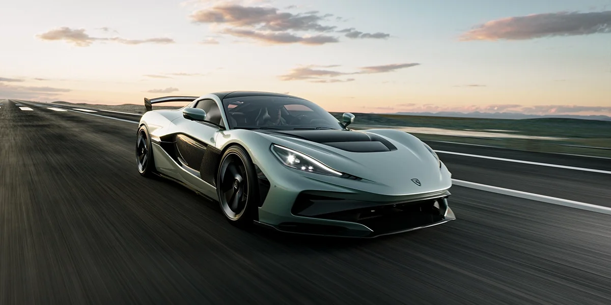 Front three-quarter view of the Rimac Nevera R electric hypercar accelerating on an open road, highlighting its aerodynamic design and LED headlights.